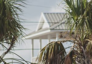 A picture of a house in the background with palm trees in the foreground, indicating that the house is built in Florida.