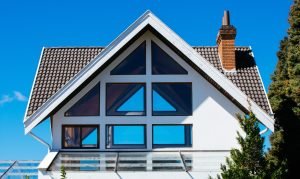 A modern looking house with a tile roof showing a chimney and not enough space for solar panels.