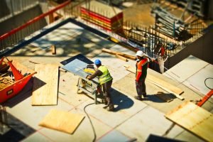 A picture of two men working inside a half-finished net-zero house surrounded by plywood.