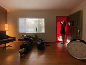 A woman is installing the red fabric part of a blower door test in the doorway of a living room.