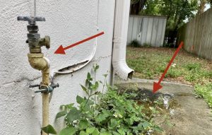 An outdoor water faucet leaking and creating a puddle on the side of the house, indicating phantom leakage and a higher water bill.