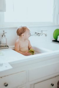 Photo of a baby taking a bath in the kitchen sink.