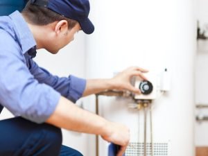 Photo of a technician adjusting a dial on a heat pump water heater.