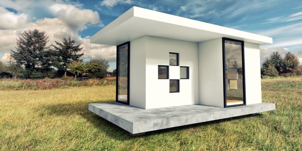 a small modern square looking house int he middle of a field.