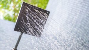 A picture of a square shower head above the camera, with hot water flowing through it.
