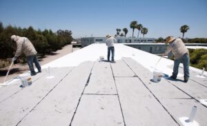 Workers retrofitting a home with a cool roof coating in the desert with spray foam polyurethane coating
