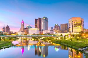 The Columbus, OH skyline at dusk with the Scioto River in the foreground