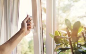 a window being cracked open showing a person's hand on the handle