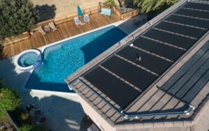 looking down at a home pool with black solar hot water panels on the roof