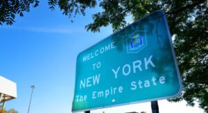 A "Welcome to New York" road sign is displayed