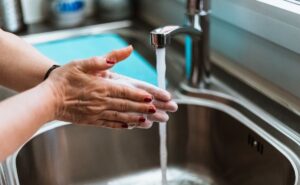 Woman washing her hands with water running from a faucet