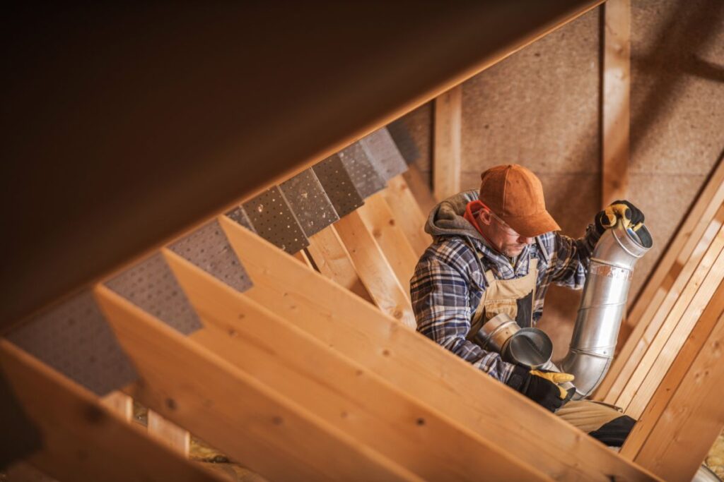 A technician installs vents for an ERV system in a home's attic