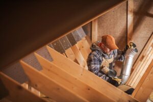 A technician installs vents for an ERV system in a home's attic