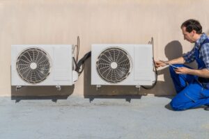 A technician installs an HRV system outside of a home