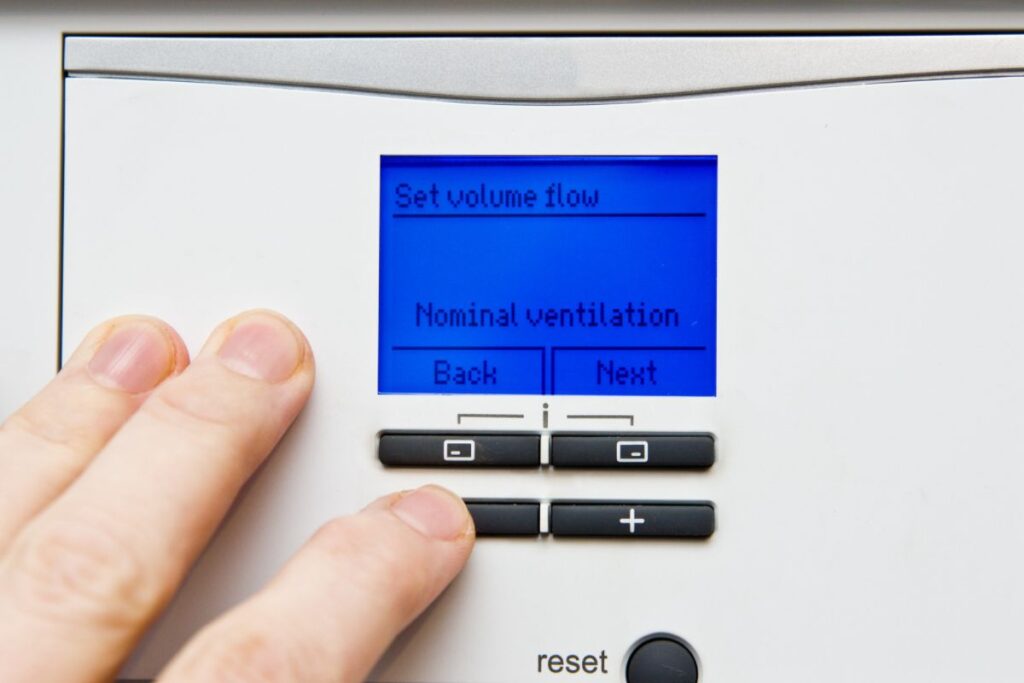 An up close shot of someone adjusting the interface of a heat recovery ventilator system