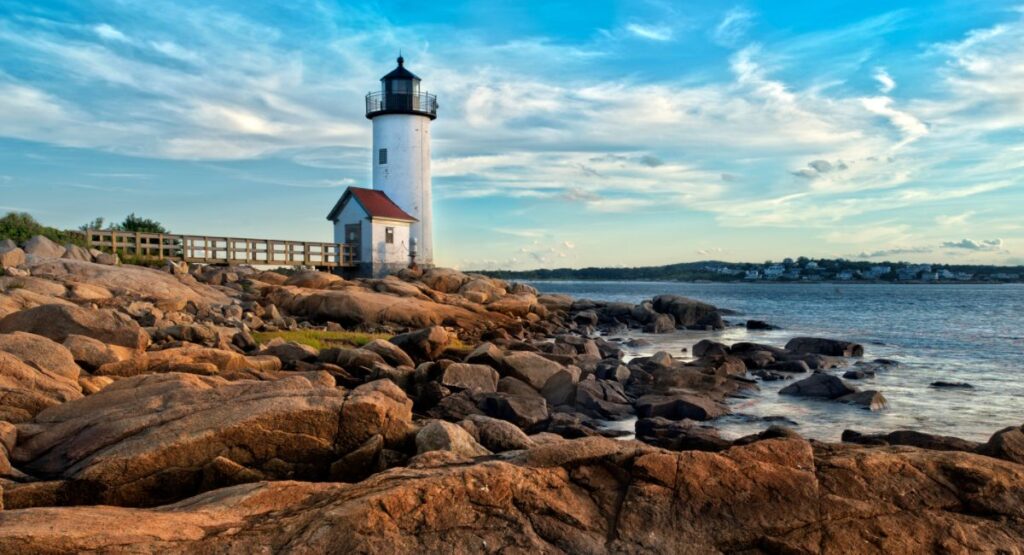 The Massachusetts coastline with rocks in the foreground and a lighthouse in the distance