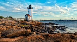 The Massachusetts coastline with rocks in the foreground and a lighthouse in the distance
