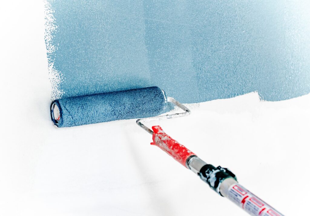 Blue eco-friendly paint is applied on a wall using a roller nap