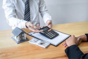 A professional sitting at a table shows a calculator displaying the cost of an HRV to a homeowner.