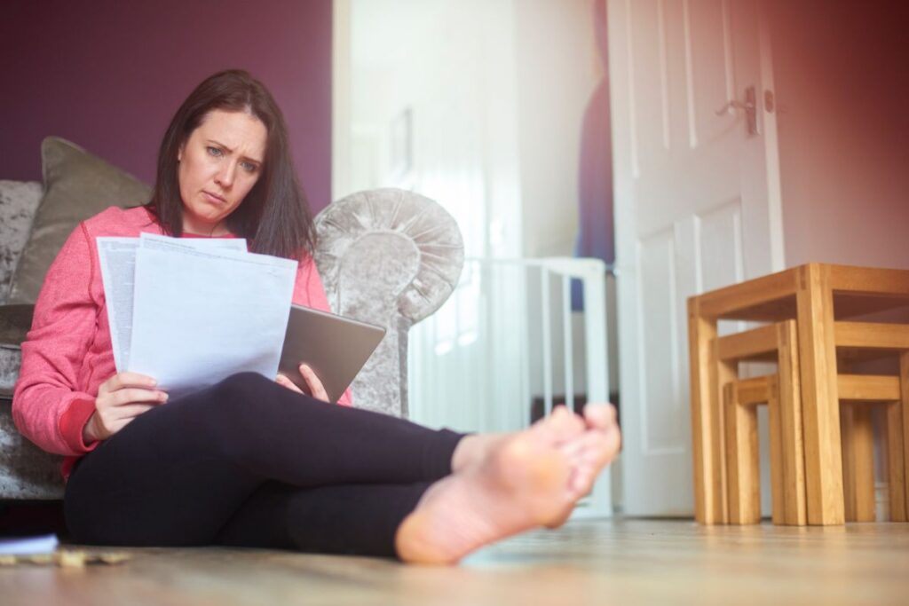A confused homeowner sits on the living room floor and looks at literature on the difference between HRVs and ERVs