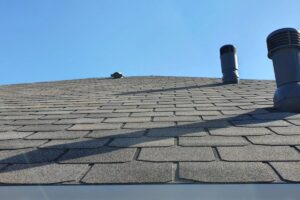 A roof with black asphalt shingles is depicted.