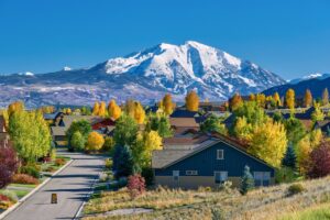 A view or rural Colorado with green space and a house in front, and mountains in the back