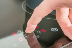 Closeup of a cook adjusting the setting on the interface of an induction cooker