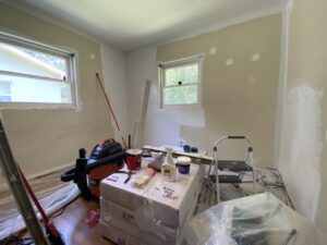 a bedroom half painted with all different paint supplies in the middle of the floor
