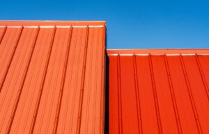 Closeup of two uneven metal roof sections on a home, one red the other orange