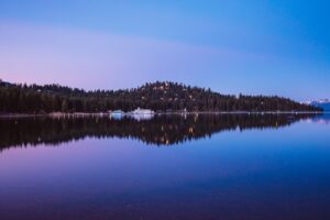 Lake Tahoe, Nevada at dusk with buildings and green hills at the water's edge