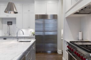 A stainless steel electric refrigerator front and center in a kitchen