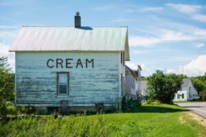 A Wisconsin farmhouse on the side of the road, with the word "cream" painted on the exterior wall