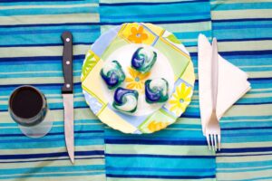 A group of four dishwasher pods on a dinner plate at a set table