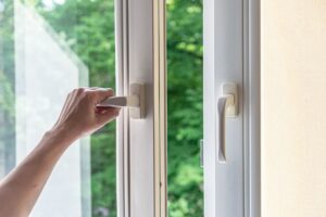 A homeowner opens a set of exterior-leading plastic windows