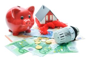A piggy bank, model home and HVAC dial mechanism on top of a pile of cash, indicating the savings from an energy recovery ventilator