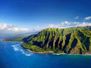 an aerial picture of the dark blue ocean and mountainous green cliff in hawaii