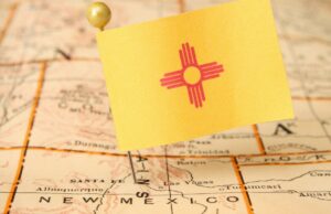 A replica of the state flag of New Mexico attached to a pin, dropped into the outline of the state on a map