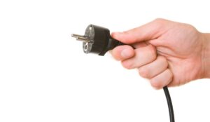 A hand holding the cord and plug of a plug-in fan