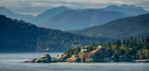 A view of several home along the British Columbia coastline with the Canadian Rockies in the background