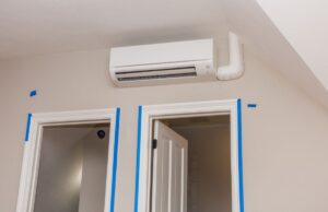 A mini-split system's internal air component above two doors near the ceiling of the room