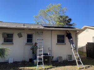 two men on ladders installing hurricane ties under the roof of a small Florida home