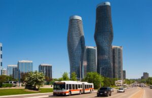 Green space and modern skyscrapers in downtown Toronto with cars on a highway in front