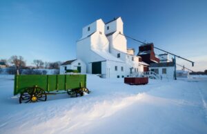 A Manitoba farmhouse during winter with a green trailer parked at front right