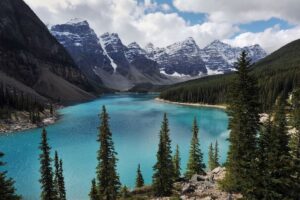 The crystal blue waters of Lake Louise in Alberta, Canada, with snow-capped mountain peaks in the background