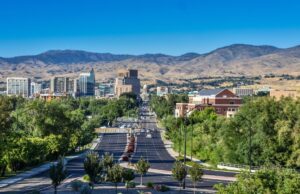 A view of downtown Boise, Idaho with green space in front and Rocky Mountain peaks in back