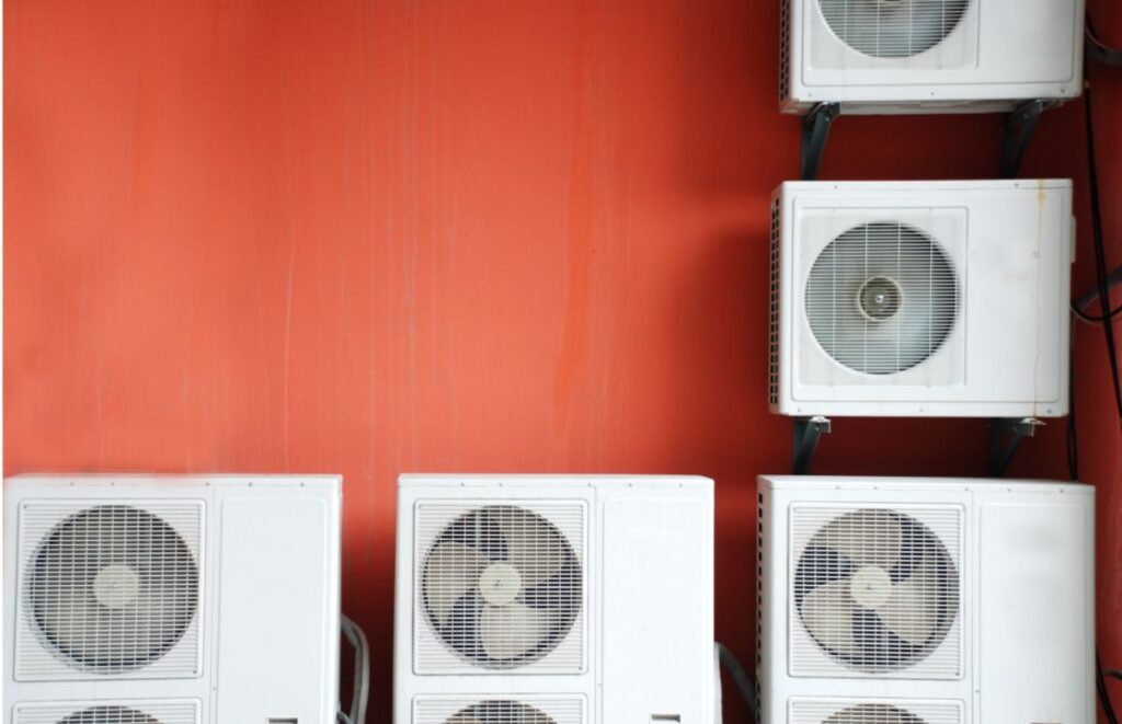 Multiple mini-split condensers mounted on a red exterior wall