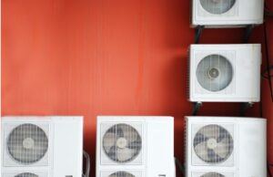 Multiple mini-split condensers mounted on a red exterior wall