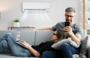 A couple of homeowners enjoying each other's company on the couch with a mini-split air handler prominently shown on the wall behind them