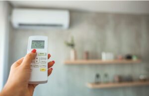 A homeowners points a remote control at the air handler unit of her mini-split system