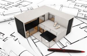 A model modular home and a pen atop some home floorplans